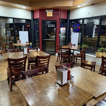 Vicky’s Restaurant - Dining area - Interior of Vicky’s Restaurant in Chicago showing wooden tables and chairs, large windows, and potted plants, with no customers present. - Burgers Near Me - Chicago, Illinois
