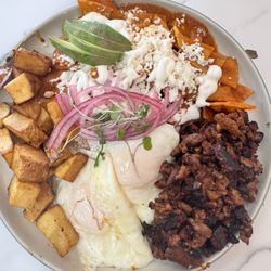 Suerte Mexican Food & Cafe - Chilaquiles, squared potatoes, meat- al pastor, two over medium eggs, sliced avocados, red onions