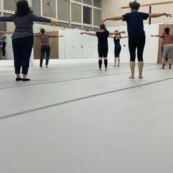 Freshly lain marley floor (11/2023). Dancers in class. Curtains can cover mirrors. Windows that open.