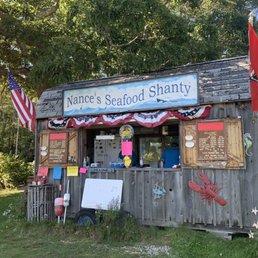 a wooden shack with a sign that says nance's seafood shanty a wooden shack with a sign that says nance's seafood shanty