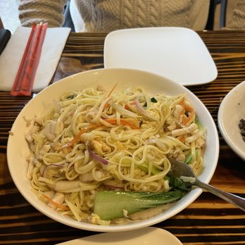 Bao - Chicken ramen noodles - A bowl of chicken ramen noodles with vegetables such as cucumber, carrots, and onions, served on a wooden table in a restaurant setting. - Asian Fusion Near Me - Pittsburgh, Pennsylvania