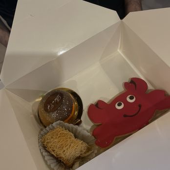 Belmo Cafe - A white box holds a red crab-shaped cookie, a small round cake with a chocolate top, and a pastry with shredded topping. - Coffee & Tea Near Me - Berkeley, California