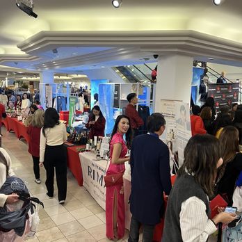 Macy's - People are browsing and interacting at various booths in an indoor shopping mall or market setting. - Department Stores Near Me - Costa Mesa, California