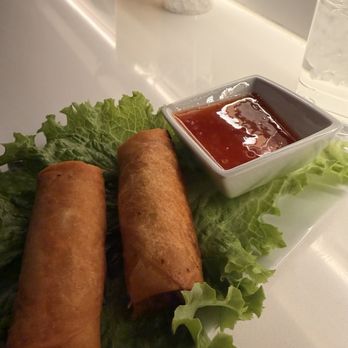 Phoxotic - Two fried spring rolls served on lettuce with a side of dipping sauce, accompanied by drinks on a restaurant table. - Vietnamese Near Me - Washington, DC, District of Columbia
