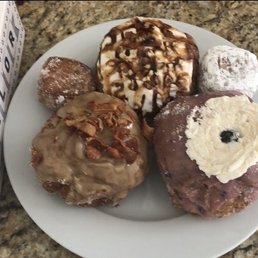 Maple Bacon doughnut, mini Cinnamon Sugar Mini, Turtle Cheesecake, Raspberry Jelly Filled Mini, and Blueberry Hill