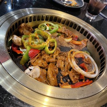 Stone Age Korean BBQ - Spicy pork belly cooking with a side of vegetables - Korean Near Me - Huntsville, Alabama Stone Age Korean BBQ - Spicy pork belly cooking with a side of vegetables - Korean Near Me - Huntsville, Alabama