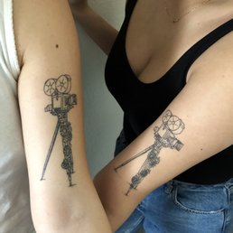 Camera tattoo with flowers wrapped around the legs Camera tattoo with flowers wrapped around the legs