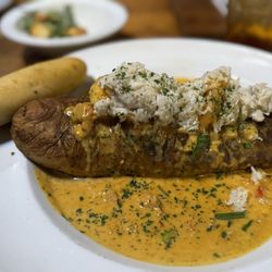 Seafood stuffed potato. Shrimp, crawfish, oysters, crabmeat with white wine lobster sauce served with a salad and bread.
