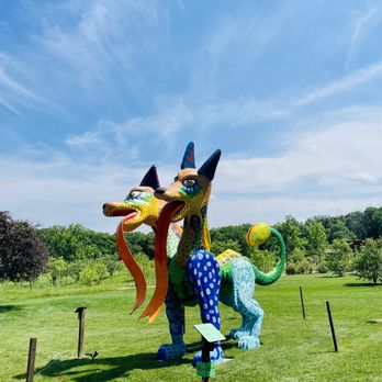 Cantigny - A vibrant, multi-colored dragon sculpture is displayed on a grassy area at Cantigny Park, featuring detailed patterns and a whimsical design. - Museums Near Me - Wheaton, Illinois