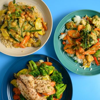 Nosh Simple - three plates of food on a blue table - Food Delivery Services Near Me