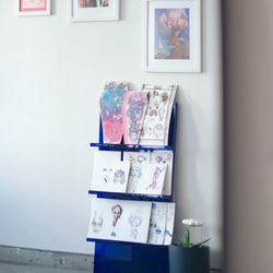 Natasha Tsozik Tattoo Studio - Shelf with the prints for sale viewed through the mirror.