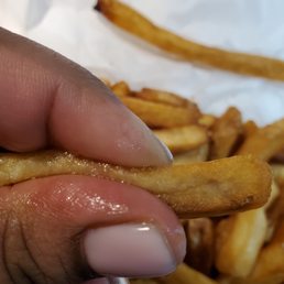 a hand holding a piece of french fries a hand holding a piece of french fries