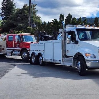 Timberline Towing and Recovery - A large white tow truck is hitched to a red fire truck, parked on asphalt with trees in the background. - Towing Near Me - Wenatchee, Washington Timberline Towing and Recovery - A large white tow truck is hitched to a red fire truck, parked on asphalt with trees in the background. - Towing Near Me - Wenatchee, Washington