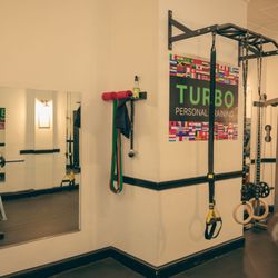 Turbo Personal Training - Wall-mounted pull-up rig with TRX, resistance bands, and Turbo Personal Training branding.