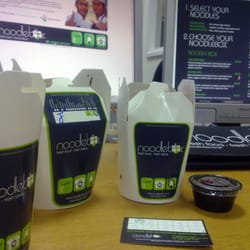 Noodlebox - The delivered noodleboxes, with dip and loyalty card with website and menu on the monitors in the background.