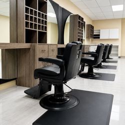 Elegant Barber Shop - Row of barber stations with black barber chairs, large round mirrors, and custom wood cabinetry.