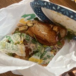 a sandwich in a paper bag on a table a sandwich in a paper bag on a table