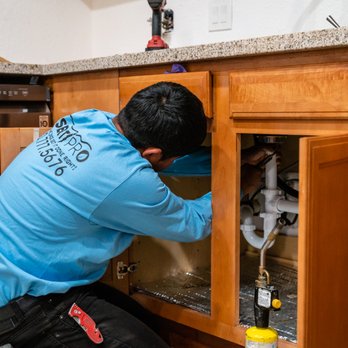 Desert Pro - a man fixing a sink in a kitchen - Plumbing Near Me Desert Pro - a man fixing a sink in a kitchen - Plumbing Near Me