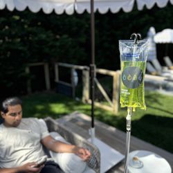 IV Elements - An IV Elements client relaxing outdoors on a shaded patio during an in-home IV therapy session.