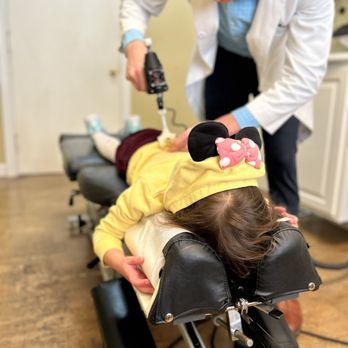 Newlin Chiropractic - Dr. Moore using one of the tools they have to adjust my daughter. He was very kind and gentle with her. - Chiropractors Near Me - Pensacola, Florida