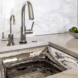 Delta Granite - Taj Mahal quartzite installed with full height Calacatta Gold backsplash and under mounted sink.