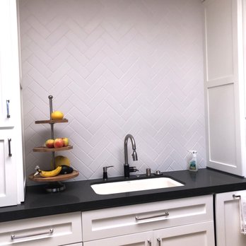 San Clemente Stoneworks - a kitchen with white cabinets and black countertops - Flooring Near Me