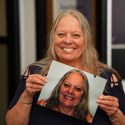 Longmont Dental Loft - Amy, an All-on-X dental implant patient, holding a photo of her smile before treatment at Longmont Dental Loft