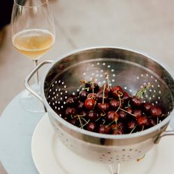Idiot's Grace Wines - Colander of organic cherries and a glass of wine.