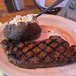Perfectly grilled medium rare New York Strip steak and a fluffy baked potato Perfectly grilled medium rare New York Strip steak and a fluffy baked potato