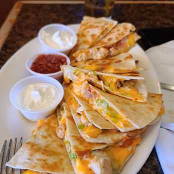 The Maple Leaf Pub - Bacon chicken ranch quesadilla. - A large oval plate holds sliced chicken, cheese, and vegetable quesadillas with three small cups of dipping sauces and a glass of beer in the background. - Bars Near Me - Westfield, Massachusetts