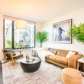 Ansel Apartments by SRG Residential - A living room with a brown couch, a coffee table, and a large window. - Apartments Near Me - San Francisco, California Ansel Apartments by SRG Residential - A living room with a brown couch, a coffee table, and a large window. - Apartments Near Me - San Francisco, California