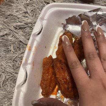 American Deli - a person's hand holding a piece of fried chicken - Chicken Wings Near Me - Norcross, Georgia