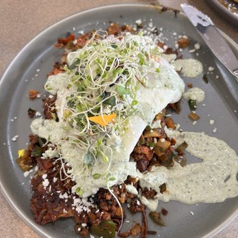 The Brunch House - Latin Heat Scramble - A dish featuring a Latin Heat Scramble with microgreens, cheese, and a creamy herb sauce, served on a gray plate. - Breakfast & Brunch Near Me - Redding, California
