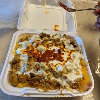 Yassa Grill - a hand holding a fork over a tray of food - Food Trucks Near Me - Lowell, Massachusetts Yassa Grill - a hand holding a fork over a tray of food - Food Trucks Near Me - Lowell, Massachusetts
