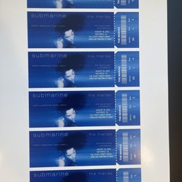 Print job - A sheet of six concert tickets for submarine's North American tour in 2024 is displayed. Each ticket has a blue background with an image of a woman's face, and includes details such as the tour name, date (August 18, 2024), location (San Diego, CA), venue (Open Air Theatre at SDSU), and section, row, and seat information. The tickets are arranged vertically, with perforated edges for separation.