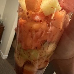 a person holding a plastic cup filled with fruit