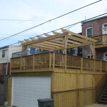 American Deck and Patio - A Washington DC row home covered carport with garage door & expansive deck & pergola.  A small Juliet Balcony deck off the master bedroom. - Patio Coverings Near Me - Bethesda, Maryland