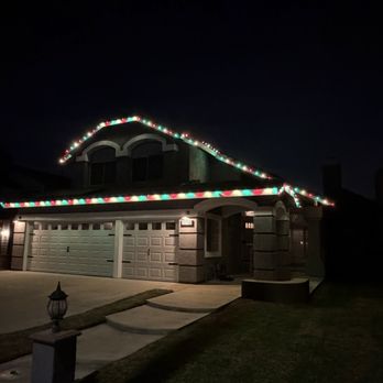 Nova Window Cleaning - Christmas lights by Nova - A two-story house with a garage is decorated with multicolored Christmas lights along the roofline at night. - Pressure Washers Near Me - Chino, California