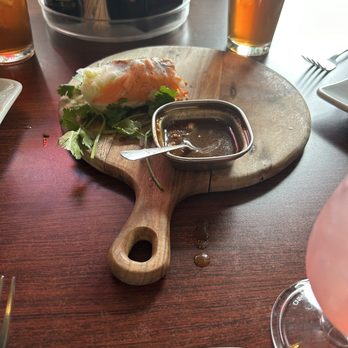 Wicked Pho - The spring rolls with grilled pork - Spring roll with dipping sauce on a wooden serving board, accompanied by drinks on a restaurant table. - Vietnamese Near Me - El Paso, Texas
