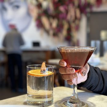 De Novo European Pub - a person holding a cocktail glass - American Near Me - Montclair, New Jersey De Novo European Pub - a person holding a cocktail glass - American Near Me - Montclair, New Jersey