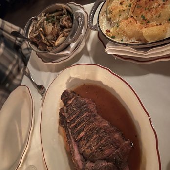 Marcel - Bone Bone-in New York Strip, Pommes Dauphinoise, and Grilled Onions - Steakhouses Near Me - Atlanta, Georgia