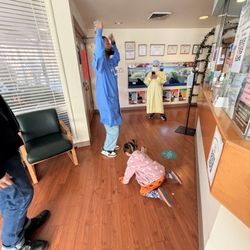 Uptown Pediatric Dentistry - Dr. Carl doing a celebratory dance and staff taking photo to commemorate first dental visit.