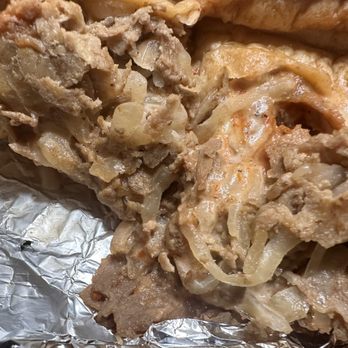 Big Bertha's Grill - slop - A detailed close-up of a cooked meat and onion filling, possibly from a pie or casserole, resting on aluminum foil. - Sandwiches Near Me - Reading, Pennsylvania