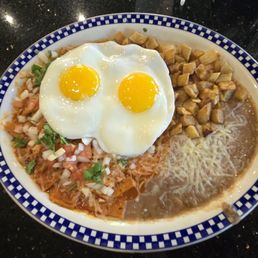 Chilaquiles. Fried tortillas drenched in salsa with two sides being warm diced potatoes and frijoles topped with two eggs. Chilaquiles. Fried tortillas drenched in salsa with two sides being warm diced potatoes and frijoles topped with two eggs.