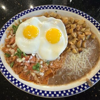 La Torta - Chilaquiles. Fried tortillas drenched in salsa with two sides being warm diced potatoes and frijoles topped with two eggs. - Mexican Near Me - Fresno, California