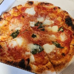 Margherita - A pizza with mozzarella cheese, tomato sauce, and basil leaves in an open pizza box.