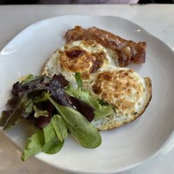 Living Room - Avocado Toast with Eggs and Bacon, garnished with a side of greens.