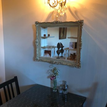 Hopfields - indoor decor - The image shows a corner of a dining room with a vintage-style mirror, a chandelier, and a table with a flower vase and condiments. - Pubs Near Me - Austin, Texas