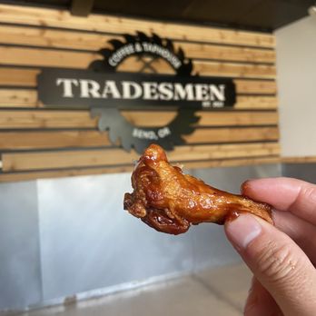 Northwest Wing Shop - a hand holding a piece of fried chicken - Chicken Wings Near Me - Bend, Oregon
