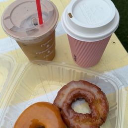 Two drinks and two freshly made glazed donuts Two drinks and two freshly made glazed donuts